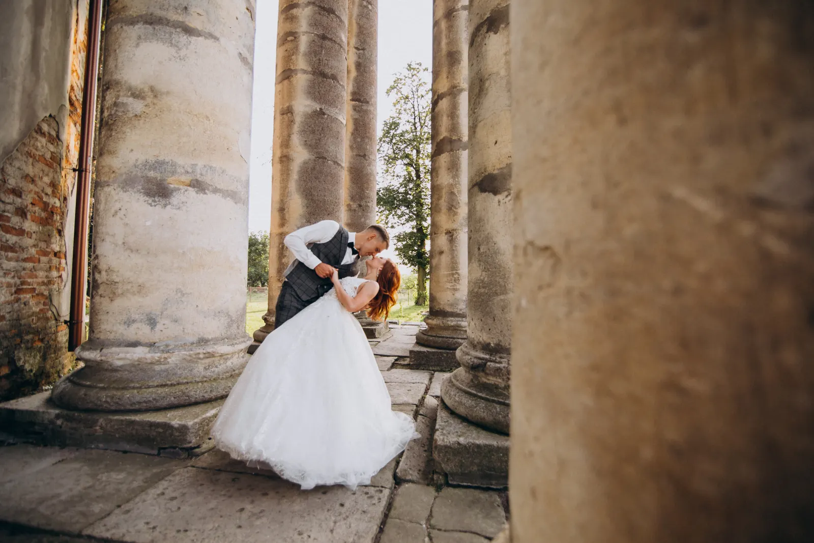 A newly married couple celebrating outdoors among stone columns